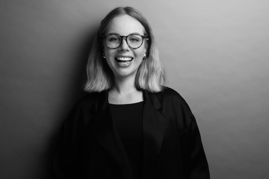 Ein Porträt von Leonie Wolf mit lächelndem Gesicht in Graustufen